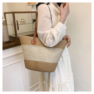 Dettaglio della borsa tote in paglia intrecciata con spalline in pelle e trama a righe