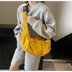 Detailed view of bright yellow crescent crossbody bag with drawstring pleats and wide strap