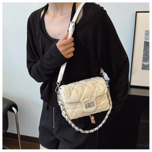 Close-up of quilted rhombic pattern and silver turn-lock on the creamy white crossbody bag