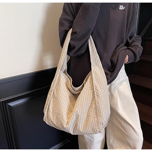 Detailed texture of large beige checkered canvas tote bag showing soft drape and material