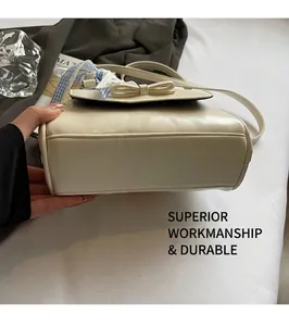 Detailed view of the reinforced flat bottom stitching on a cream Boston handbag