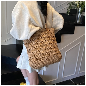 Detailed crochet openwork pattern on a natural straw tote bag with a slim leather strap