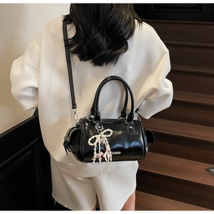 Borsa Boston in vernice nera con ciondolo a fiocco di perle portata da una modella