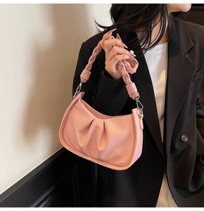 Detail of light pink pleated hobo bag with woven handle and silver metal hardware hooks