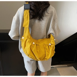 Detail of yellow waterproof nylon dumpling bag with adjustable drawstrings and side buckles