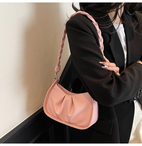 Detail view of pink pleated underarm bag with lychee grain texture and woven strap