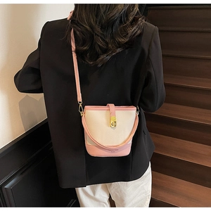 Détail du sac seau crème et rose avec fermoir doré porté par un mannequin