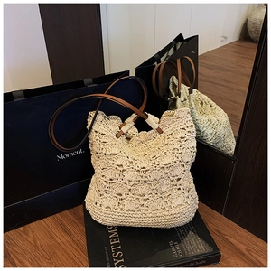 Detailed close-up of handmade woven straw tote with floral pattern and leather straps
