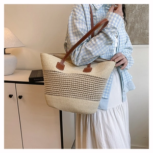 Dettaglio della borsa tote in paglia intrecciata con spalline in pelle marrone
