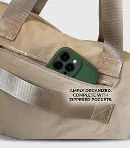 Detail of a side zipper pocket on a beige nylon bag showing deep storage for a smartphone
