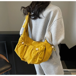 Back view of a large bright yellow nylon dumpling shoulder bag on a model's outfit