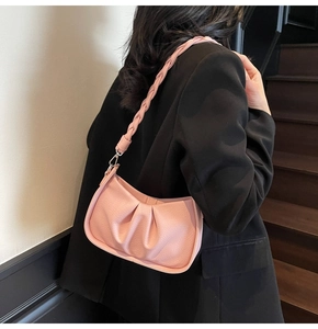 Detail of pink pleated dumpling bag with textured leather and a thick woven shoulder strap