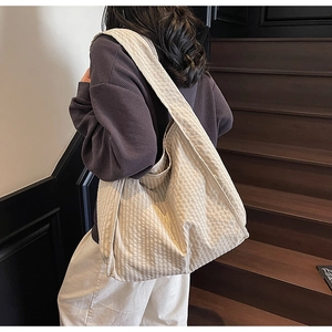 Detail of large canvas tote bag featuring a beige plaid pattern and wide shoulder strap
