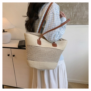 Borsa tote in paglia intrecciata con spalline in pelle marrone indossata in stile spiaggia