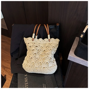 Close-up of woven straw bucket bag with scalloped edges and brown leather handles