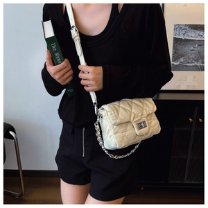 Close-up of beige quilted crossbody bag featuring silver metal twist lock and chain strap