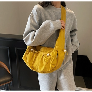 Detail of yellow pleated dumpling crossbody bag with white drawstring toggle