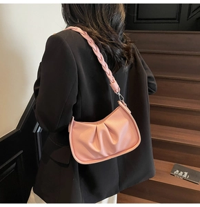 Pink pleated dumpling bag with woven shoulder strap shown in a real-life wearing scene