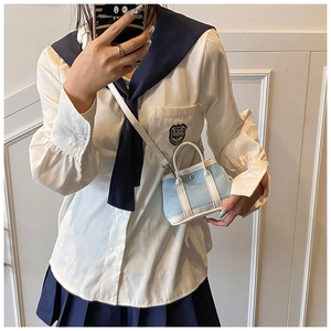 Detail of light blue canvas bucket bag with white leather handle and straps