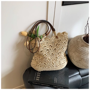 Detail of hand-woven straw tote with wavy edges and premium brown leather straps