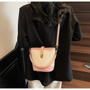 Gros plan du sac seau contrasté avec texture litchi et boucle dorée rotative élégante