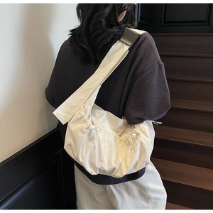 Detail of minimalist pleated nylon crossbody bag in beige with adjustable drawstring side
