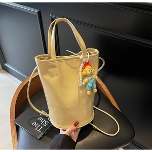 Detail of beige wrinkled patent leather bucket bag with pearl charm and fashion logo