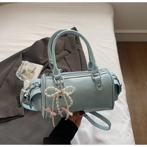 Dettaglio borsa Boston azzurra con ciondolo a fiocco di perle e placca logo