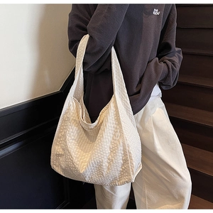 Detail of waffle textured tote bag in cream white showing bubble fabric and wide shoulder strap