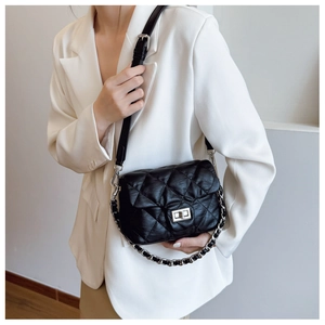 Close-up of black quilted leather shoulder bag with silver twist lock on white blazer