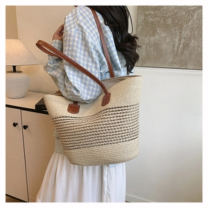 Dettaglio borsa tote in paglia intrecciata con manici in pelle e trama a righe