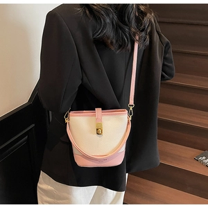 Sac seau contrasté rose et crème avec fermoir doré porté par un mannequin