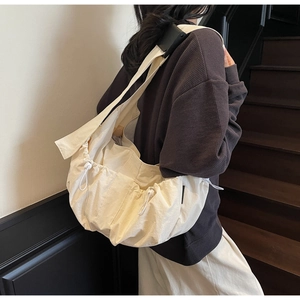 Detail of off-white tote bag showing adjustable wide strap and multiple drawstring pockets