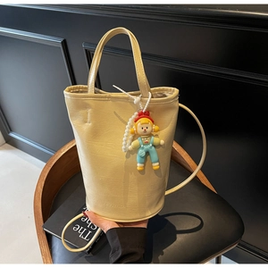 Detailed macro of beige bucket bag showing textured PU leather and fashion branding