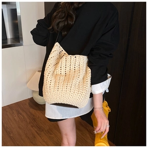 Detail of hand-woven cream crochet bucket bag showing delicate hollow floral pattern and black strap