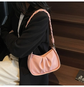 Detailed close-up of pink pleated leather shoulder bag with woven strap and metal hooks