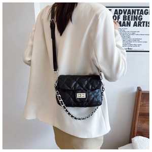 Detail of black quilted leather crossbody bag with silver twist lock and chain strap