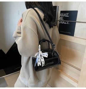 Detail of black patent leather handbag with bow and blue checkered ribbon on a model