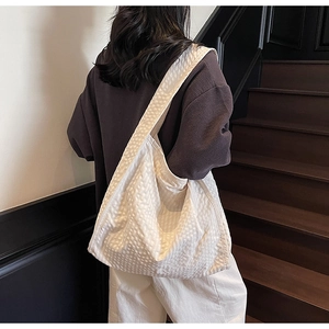 Detail of white bubble texture fabric on large tote bag shown on model in indoor setting