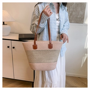 Dettaglio della borsa tote tessuta a mano con fibre rosa e beige e manici in pelle marrone