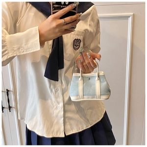 Close-up of a light blue mini canvas bucket bag with white handles and metal studs
