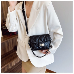 Detail of black quilted leather shoulder bag with silver chain strap and twist-lock