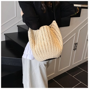 Detail of beige woven bucket bag with textured wave pattern and black leather strap
