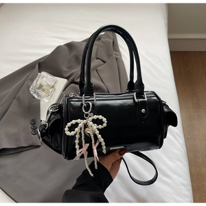 Dettaglio della borsa Boston nera lucida con ciondolo a fiocco di perle e hardware argento