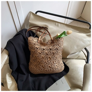 Detail of hand-woven straw bucket bag with leather handles on minimalist armchair