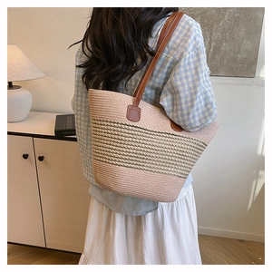 Dettaglio della borsa tote intrecciata rosa e beige con cinturini marroni in interno minimal