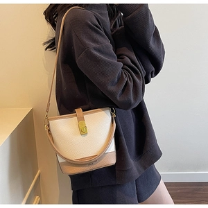 Vue détaillée du sac seau crème avec bordure marron et fermoir doré porté par le modèle
