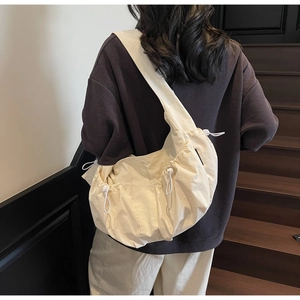 Detail of minimalist beige dumpling crossbody bag featuring soft fabric and drawstring closure