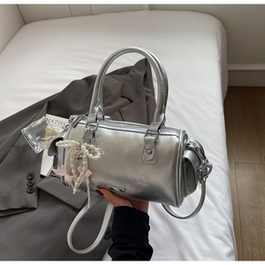 Dettaglio borsa Boston argento con ciondolo di perle e fiocco rosa su giacca grigia
