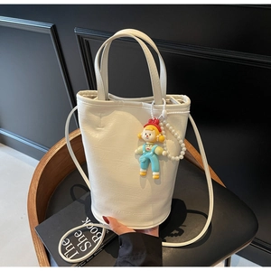 Detailed view of white bucket bag with 'FASHION' embossing and cute cartoon pendant